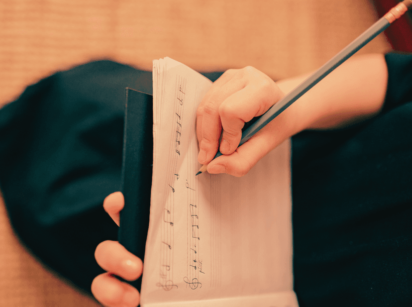 Close up of a person writing music notation in a note book